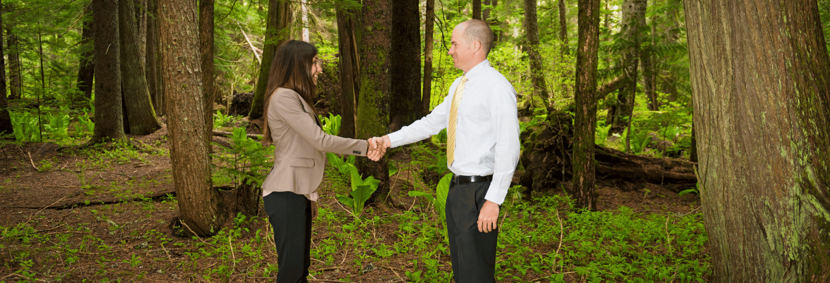 Man and woman shaking hands in a remote forest location