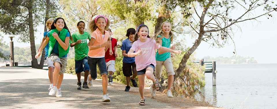 Children running on a path near a lake.